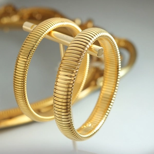 Minimalist gold snake chain textured bangles on a display stand with polished metallic finish