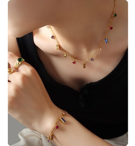 Dettaglio di un set di gioielli dorati con zirconi colorati indossati da una modella
