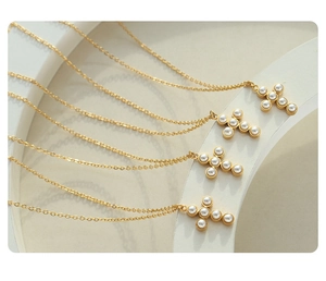 Detailed view of cross pearl pendant necklaces on white elegant display stand