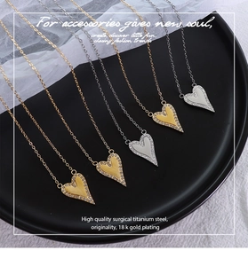 Detail von fünf Titanstahl-Herzketten mit Zirkonia in Gold und Silber auf Schwarz