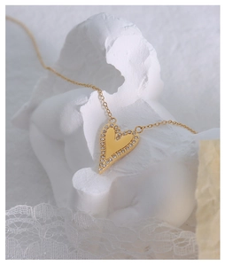 Detailaufnahme von goldenem Herzanhänger mit Zirkon-Inlay an einer Titanstahlkette