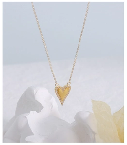 Detailansicht eines goldenen Herzanhängers mit Zirkonia-Inlay an einer feinen Kette