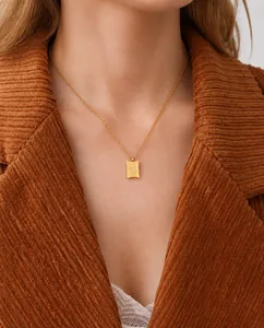 Dettaglio di una collana dorata con ciondolo Good Luck indossata da una modella