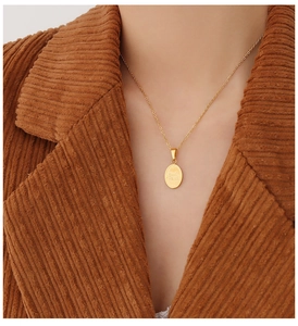 Dettaglio della collana con ciondolo Good Luck dorato su sfondo giacca di velluto