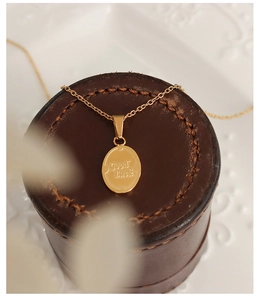Dettaglio della collana con ciondolo ovale d'oro inciso Good Luck su pelle