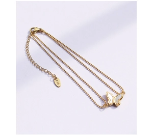 Detail of 18K gold butterfly pendant on triple-strand beaded anklet with extension chain