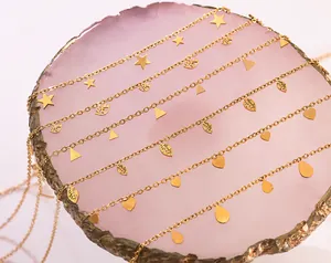 Gros plan de six colliers dorés avec divers pendentifs sur un plateau minéral rose