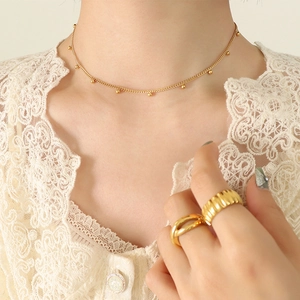 Gargantilla de cuentas doradas y conjunto de anillos lucidos por una modelo
