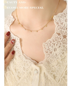 Détail du collier avec pendentifs mauvais œil plaqué or 18 carats porté sur de la dentelle