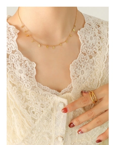 Collier à pendentifs feuilles dorées et bague croisée portés avec élégance par un mannequin