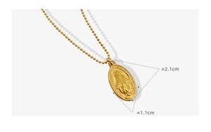 Macro view of gold beaded chain with oval Virgin Mary pendant showing detailed engraving