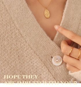 Detail of gold beaded necklace with oval Virgin Mary pendant and minimalist gold rings