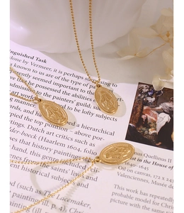 Close-up of golden oval religious pendants on beaded chains with artistic book background