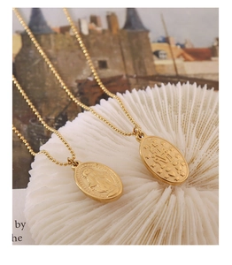 Detailed close-up of double-sided gold oval relief pendants with religious iconography
