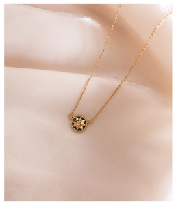 Detail of 18K gold-plated starburst necklace with green stone on pink silk