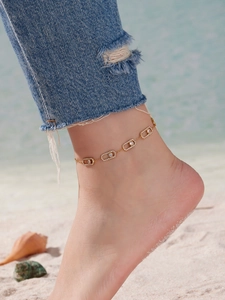 Détail de la chevillère dorée avec cristaux de zircon mobiles sur fond de plage ensoleillée