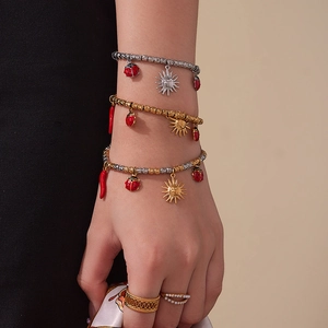 Beaded bracelets set with fruit pendants and pearl ring on model in warm studio lighting
