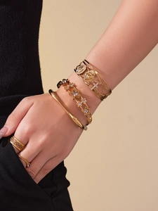 Détail de bracelets étoiles et bagues en acier plaqué or 18 carats portés par un mannequin