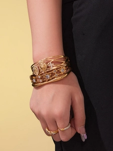 Détail de bracelets superposés en or 18 carats avec breloques étoile et coeur
