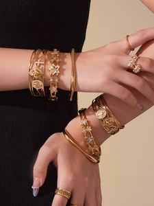 Détail de bracelets superposés en acier inoxydable plaqué or 18k avec étoiles et zircons