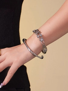 Détail d'un ensemble de bracelets argentés avec anneau poli et chaîne étoilée en zircone
