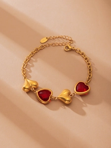 Detail of gold-plated stainless steel heart bracelet with sparkling red crystals
