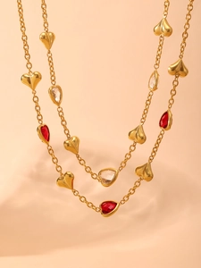 Detail of gold layered chain necklace with red and clear heart-shaped stone pendants