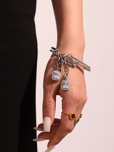 Detail of silver link chain bracelet with large rectangular clear gemstone and figure-8 charm