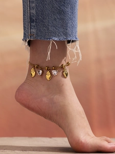 Close-up of a gold anklet with heart pendants and crystals worn on the ankle