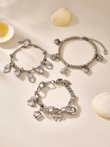 Detail of silver stainless steel bracelets with heart and bear charms on white shell