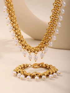 Détail du collier et bracelet à grosse chaîne dorée avec pendentifs perles blanches
