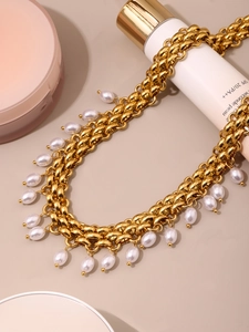 Détail du collier à grosse chaîne dorée orné de perles blanches élégantes en goutte