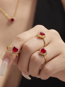 Close-up of three luxurious red heart zircon rings on fingers with matching necklace