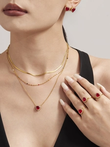Macro shot of layered gold necklace and heart-shaped red zircon jewelry set on model