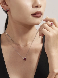 Detail of red heart zircon necklace and earrings set on model with silver-tone finish