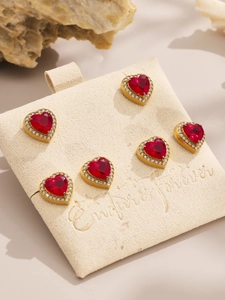 Macro detail of red heart zircon pendant set with sparkling diamond halo on suede stand