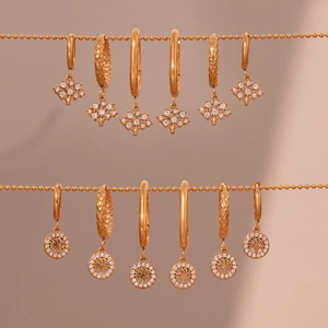 Boucles d'oreilles créoles arbre de vie dorées avec zircons sur fond dégradé doux