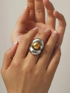 Gros plan d'une bague vague argentée double couche avec perle dorée sur la main