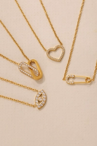 Detailed view of evil eye necklaces featuring heart and safety pin pendants with zircons