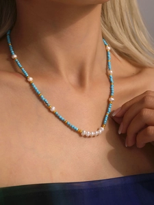 Detailed close-up of beaded necklace with turquoise stones and freshwater pearls