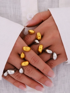 Macro view of stacked gold and silver teardrop rings with smooth organic liquid metal finish