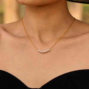 Collana minimalista in acciaio inossidabile dorato con sei perle bianche su modella