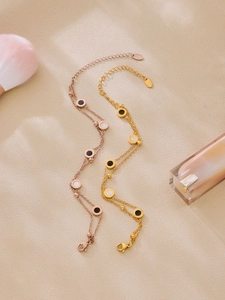 Detail von Armbändern in Gold und Roségold mit römischen Ziffern auf beigem Grund