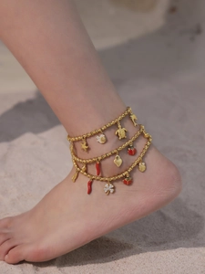 Gold multi-layer anklet with turtle and starfish charms on a beach setting