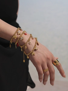 Detailed view of gold beaded charm bracelets with heart and clover pendants on a wrist