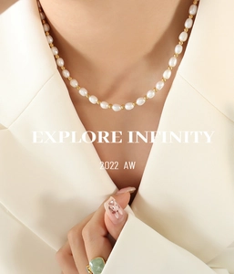 Close-up of baroque freshwater pearl necklace with gold beads on a beige blazer
