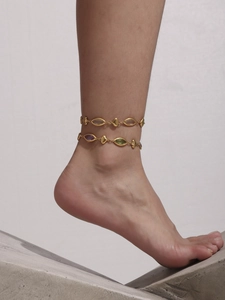 Détail de bracelets de cheville dorés avec pierres marquises violettes, vertes et cœurs