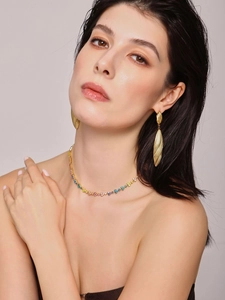 Close-up of golden teardrop earrings and colorful gemstone necklace on female model