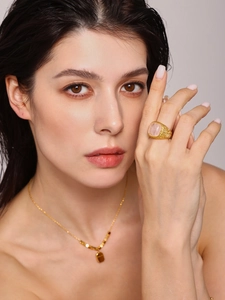 Detailed close-up of woven gold ring with large pink stone inlay on model hand