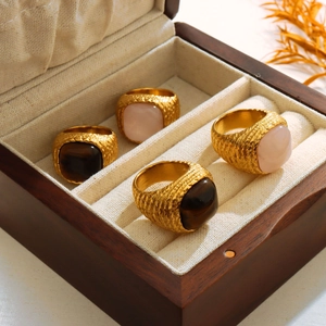 Detailed view of four retro 18K gold-plated rings with tiger eye and rose quartz stones